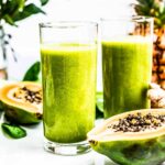 Two tall glasses of papaya spinach smoothie.
