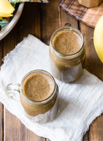 Two glass jars full of chocolate banana smoothie.