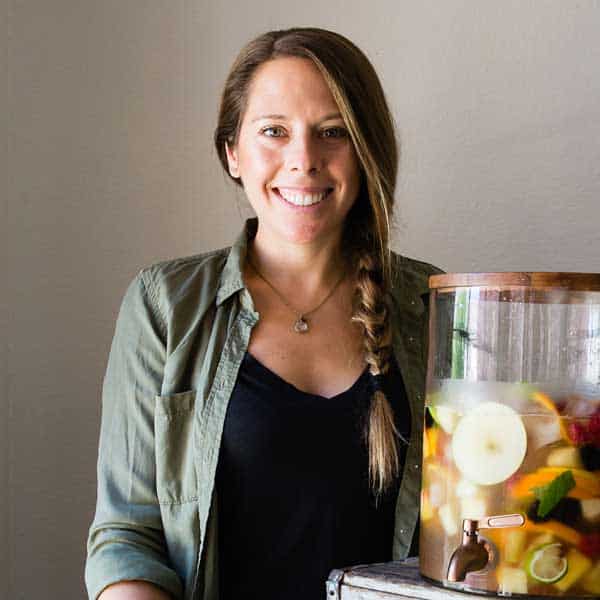 Jen Hansard beside container of fruit sangria.
