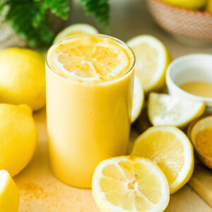Delicious lemon smoothie in the glass surrounded by fresh cut lemons.