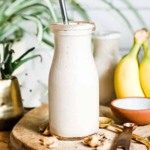 Straw in a glass carafe of creamy banana smoothie.