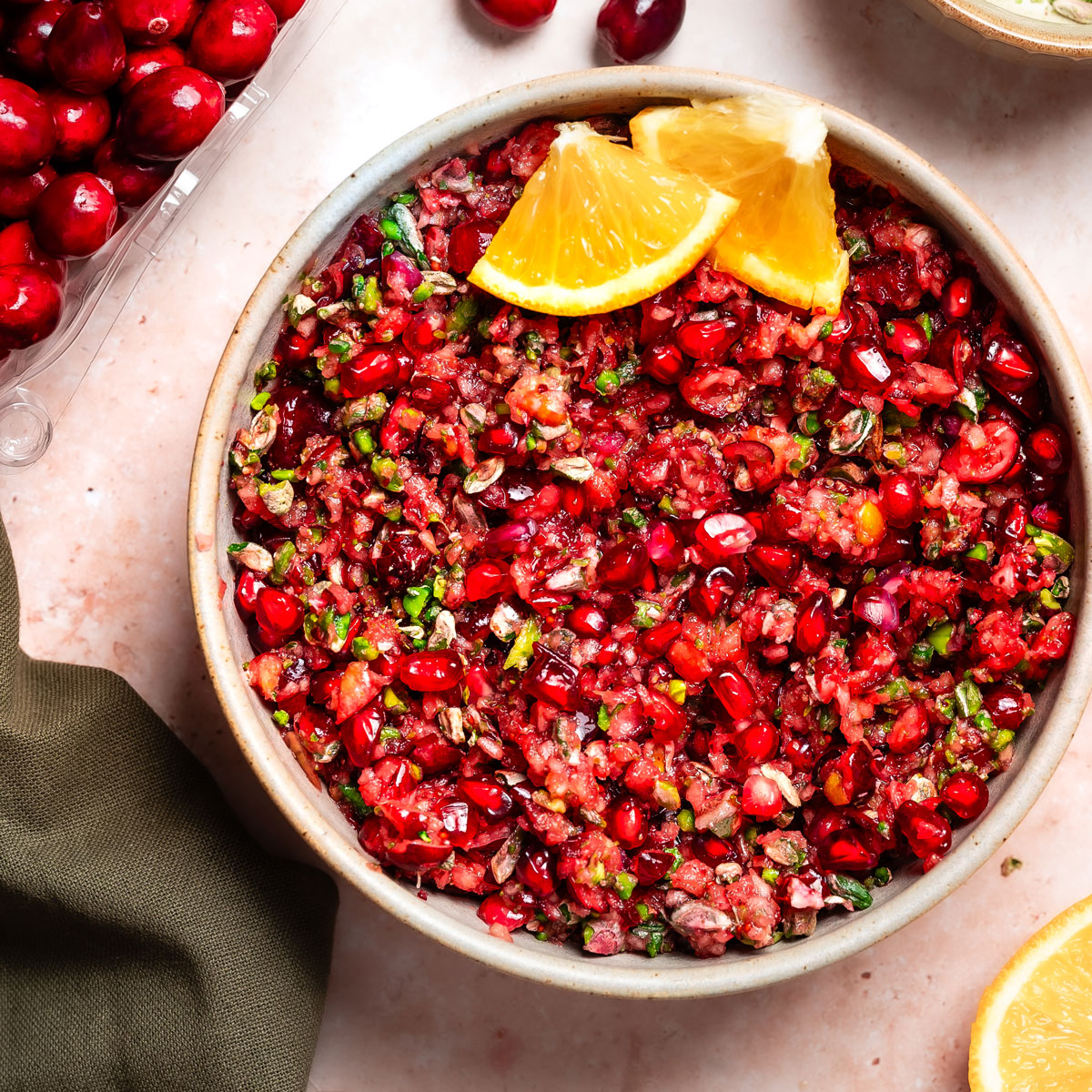 Bowl of cranberry relish with decorative orange wedges.