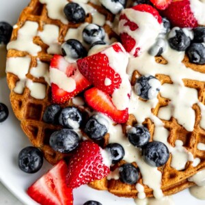 Vegan waffle topped with fruit and cream.