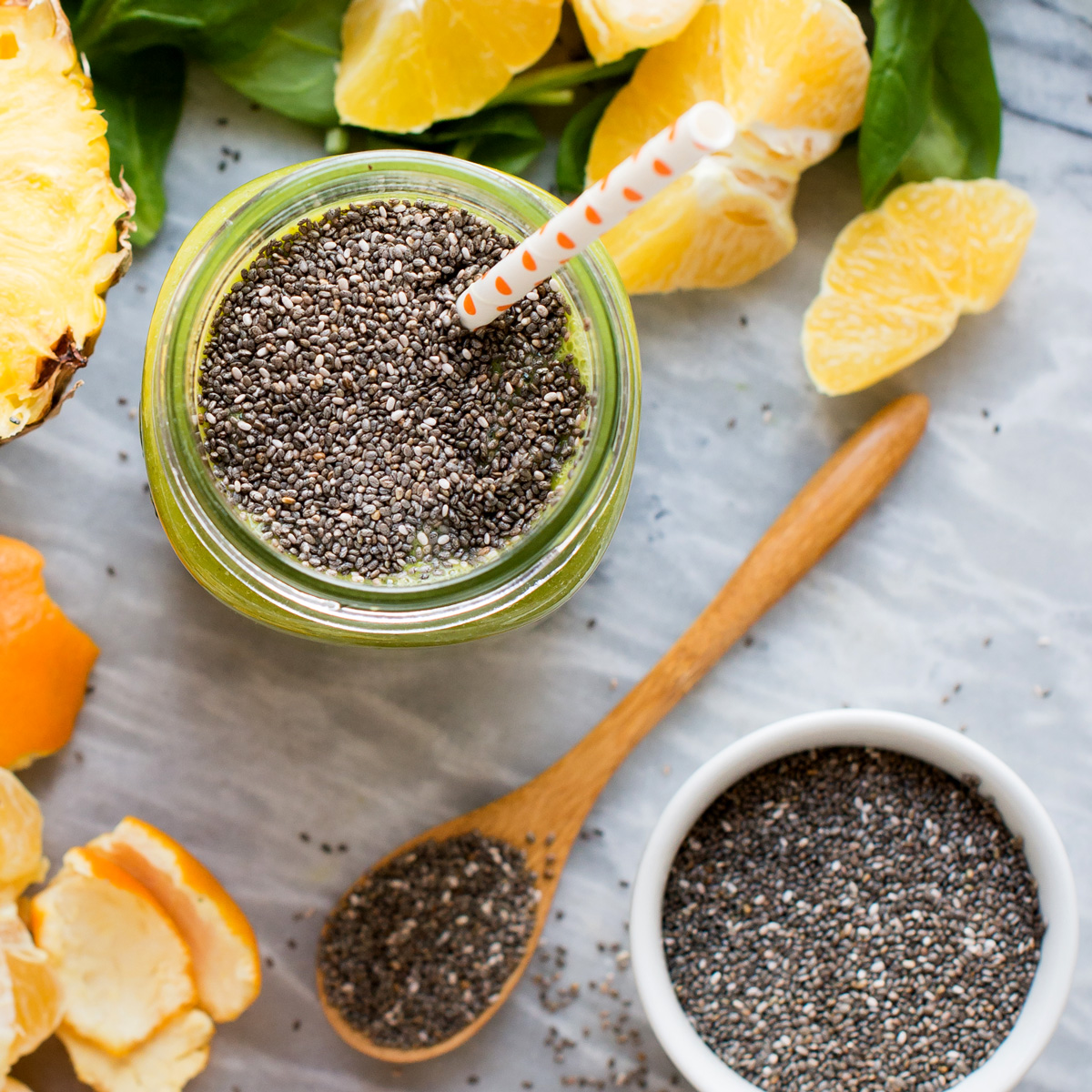 Glass of chia seed smoothie on marble counter with bowl of chia seeds.