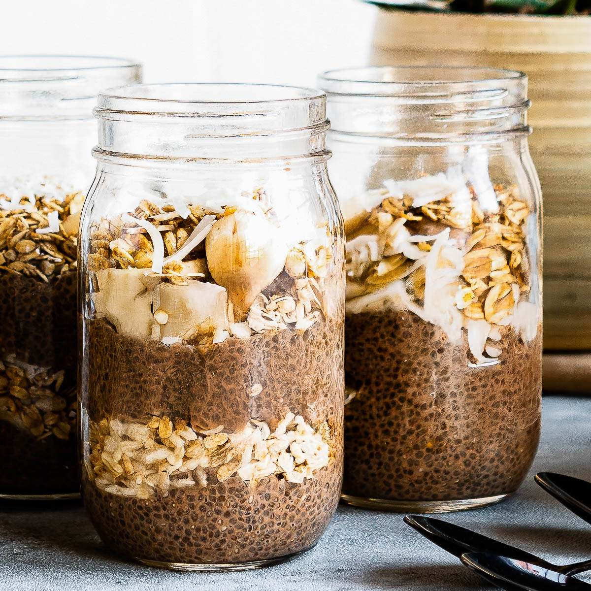 3 jars of chocolate chia pudding layered with fresh fruit and granola.