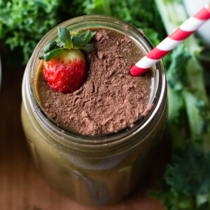 Chocolate strawberry smoothie with a straw and a strawberry.