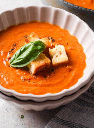 Bowl a fire-roasted tomato soup with croutons and fresh basil leaf on top.