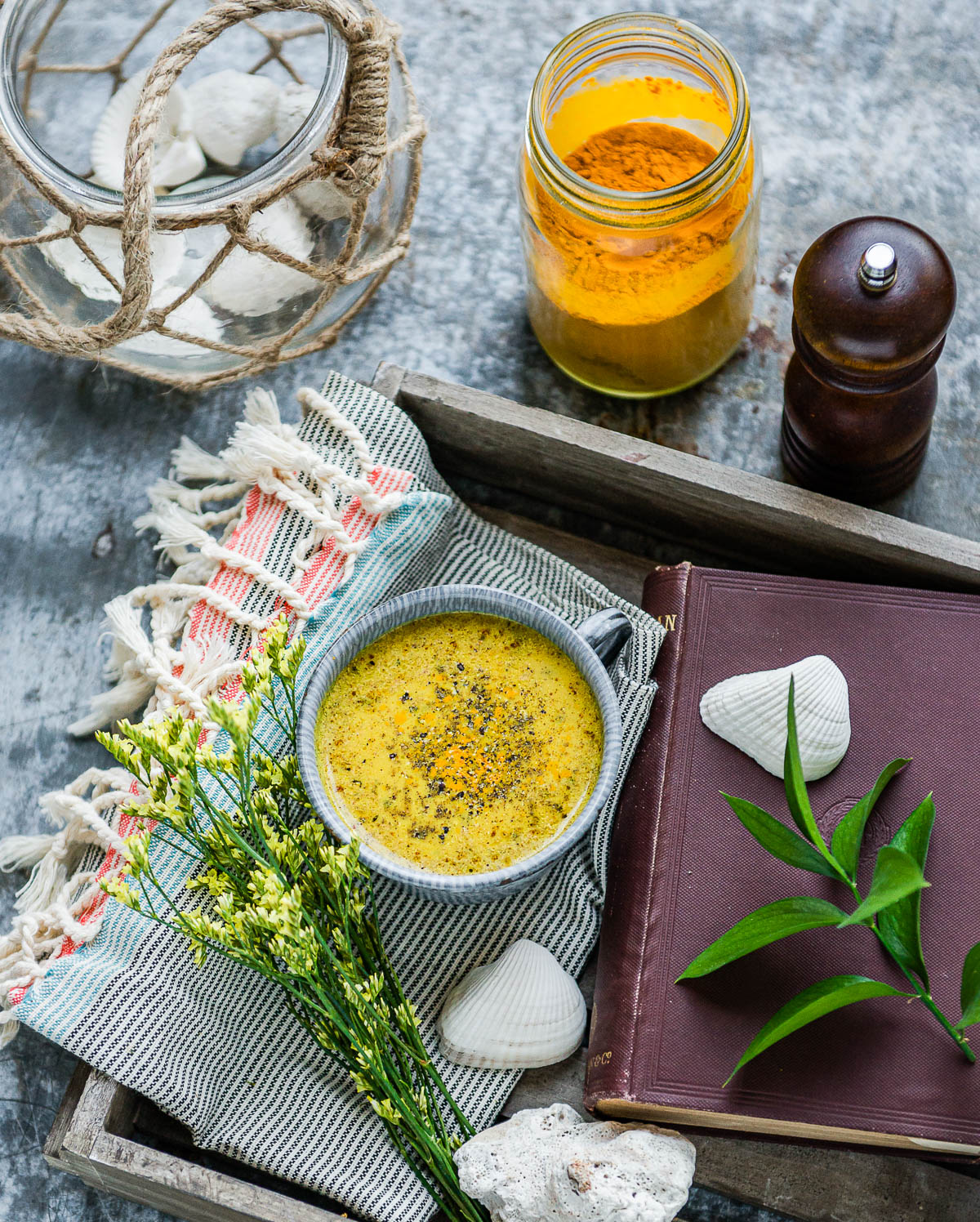 Mug of turmeric milk sitting on a wooden tray next to a book.