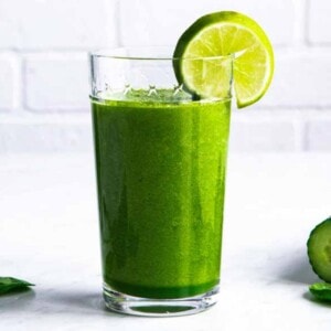 Green smoothie in a tall glass with a lime wedge.