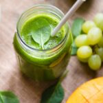 Green tea smoothie in a jar next to green grapes.