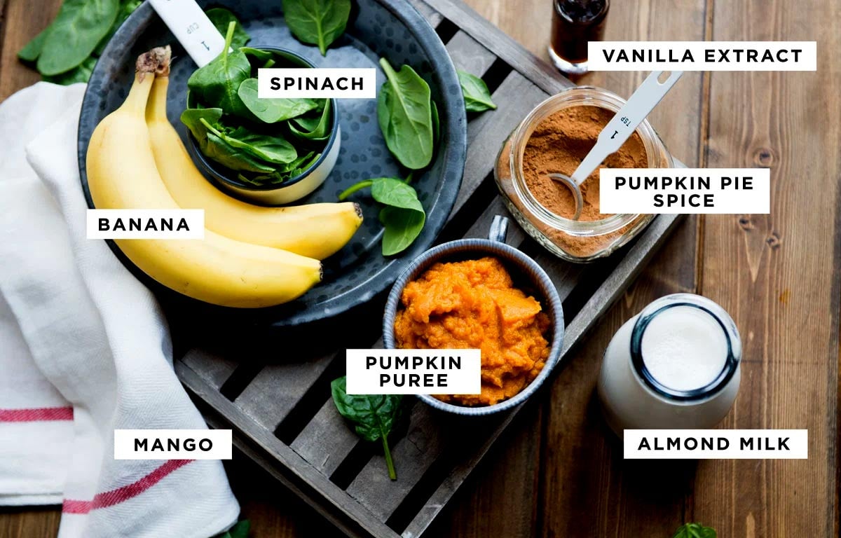 Ingredients for a pumpkin smoothie recipe in bowls on wooden table.