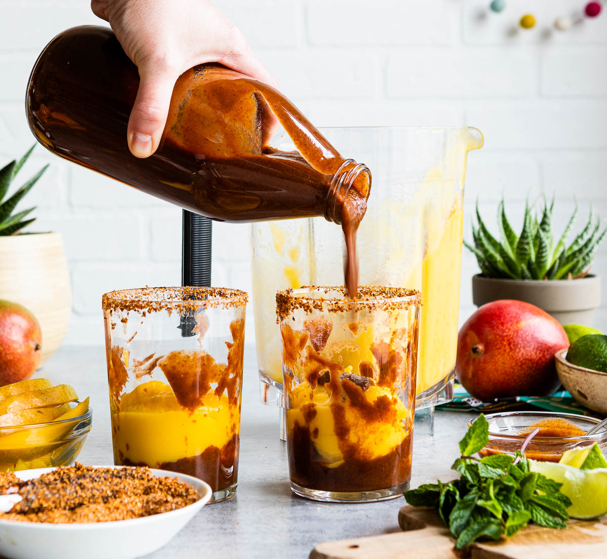Layering mango and chamoy sauce in glasses of mangonada recipe.