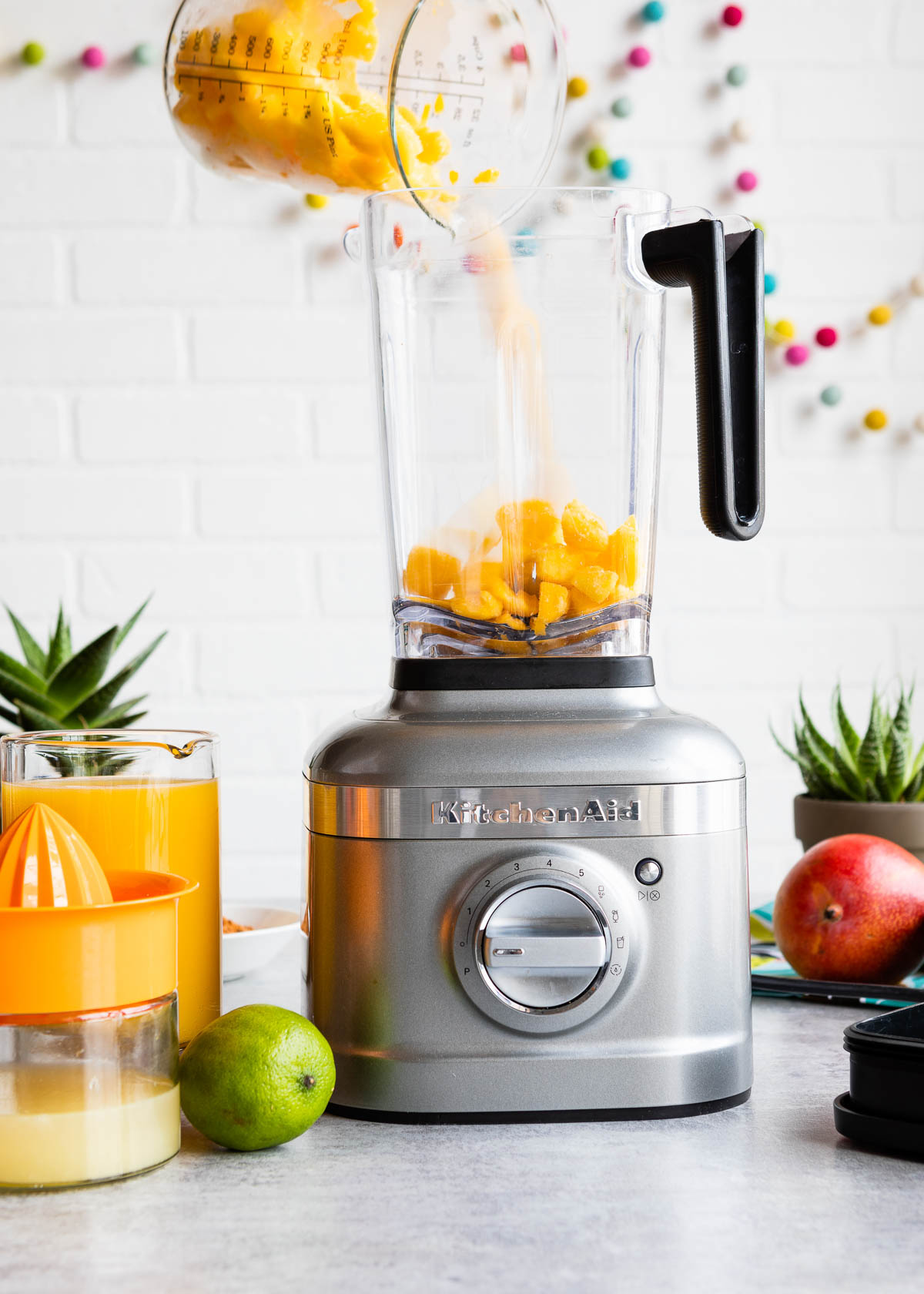 Adding sliced mango pieces into a blender.