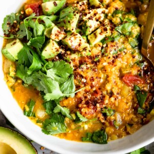 Bowl of red lentil soup topped with diced avocado.