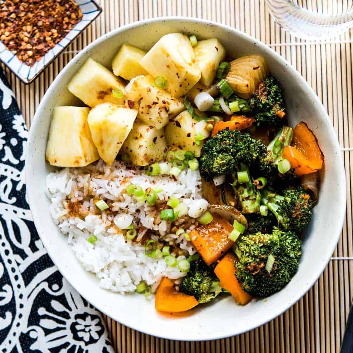 teriyaki rice bowl with pineapple, broccoli and carrots in a white bowl.