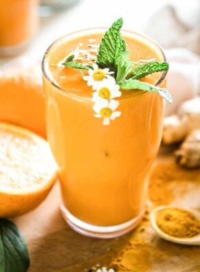 Tall glass of peach-colored honey turmeric smoothie.