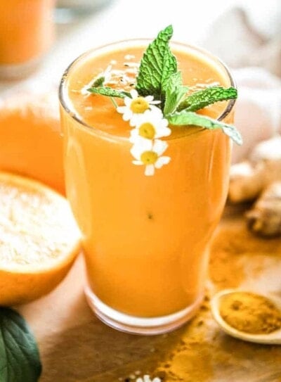 Tall glass of peach-colored honey turmeric smoothie.