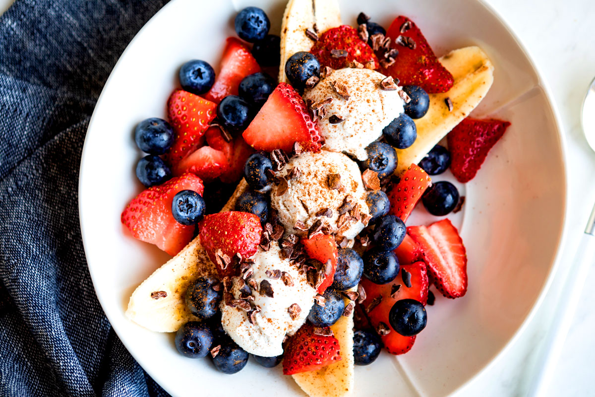 Sliced banana and fruit with ice cream to make vegan banana split.