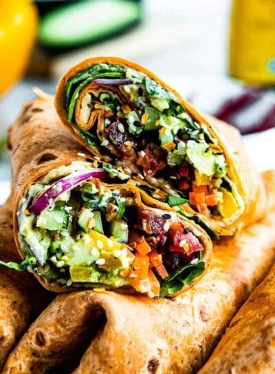 Halved vegetable wrap piled on other wraps.