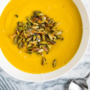 Pumpkin seeds in a bowl of bright pumpkin soup.