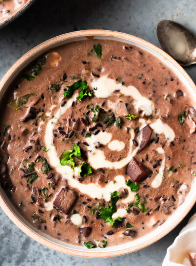 Spoon next to a bowl of vegan creamy wild rice soup.