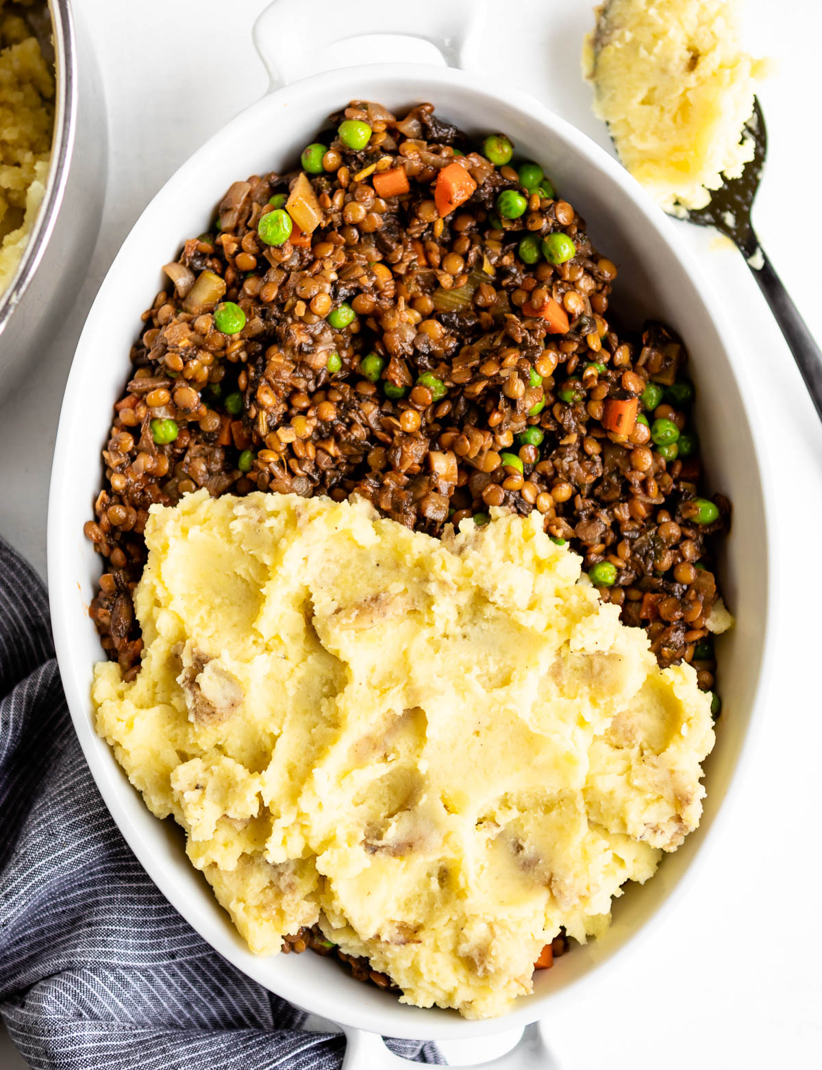 Vegetarian shepherd\'s pie partially covered with mashed potato topping.