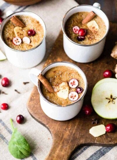 Three white mugs of warm wassail drink.