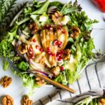 Winter pear salad recipe with gold fork on white table top.