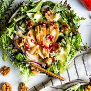 Winter pear salad recipe with gold fork on white table top.