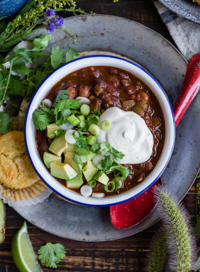 Bowl of chili topped with sour cream, avocado, and green onions.